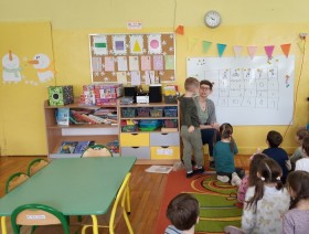 Zdjęcie z zajęć edukacyjnych w przedszkolu. Na zdjęciu widoczny jest praownik Urzędu Statystycznego oraz kilkoro dzieci.